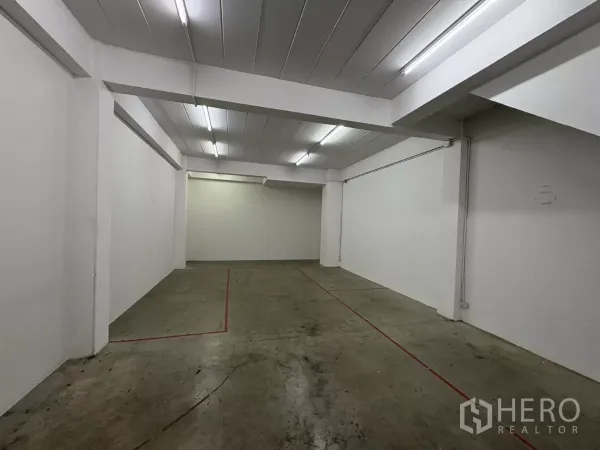 Factory for rent in Phra Samut Chedi, Samut Prakan - Ground-floor storage area with fluorescent lighting and concrete floor.
