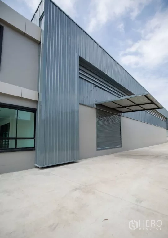 Factory for rent or sale in Bang Len, Nakhon Pathom - Side elevation with corrugated metal cladding, roller shutter door and covered loading canopy.