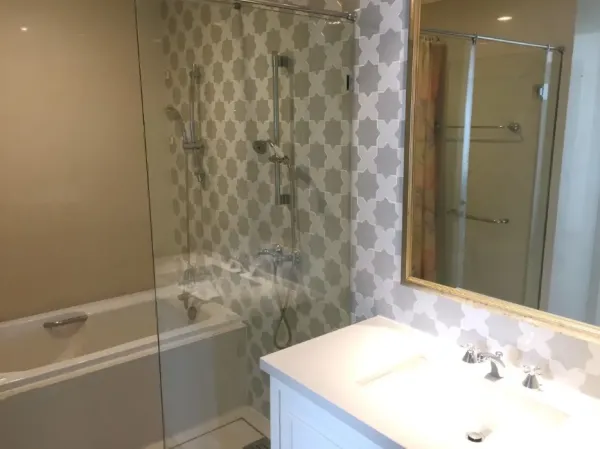 คอนโด ให้เช่าหรือขายในKhlong Toei, Bangkok - ห้องน้ำโมเดิร์นพร้อมฝักบัวกั้นกระจกเหนืออ่างอาบน้ำ ผนังลายกราฟิก และอ่างล้างหน้าพร้อมกระจก