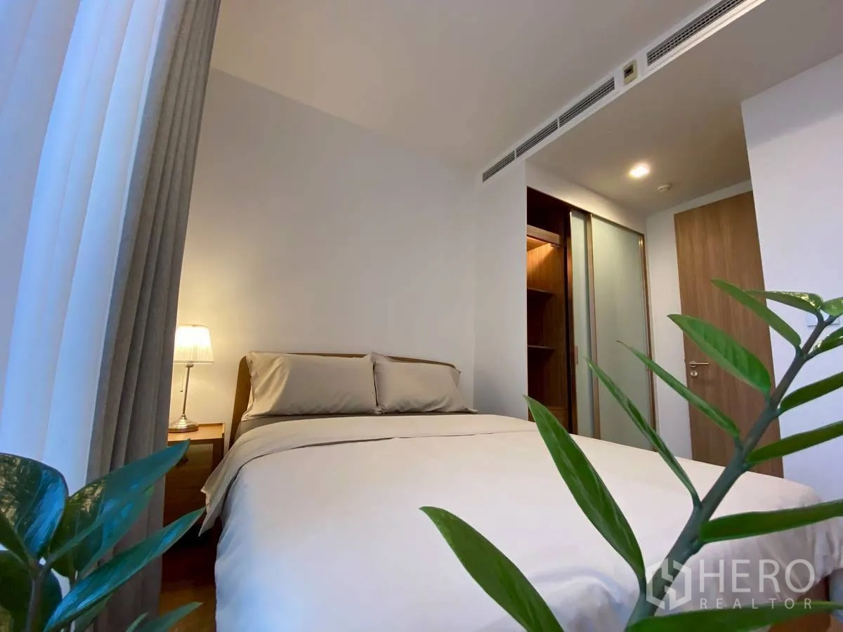 Condominium for rent in Watthana, Bangkok - Bedroom angle with bed, bedside lamp, indoor plant, and walk-in wardrobe.