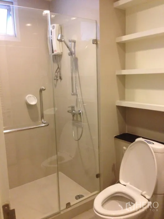Condominium for rent in Khlong Toei, Bangkok - Shower room with glass enclosure, handheld shower and built-in white shelving.
