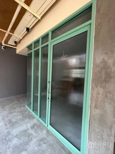 พื้นที่ขายปลีก ให้เช่าในWatthana, Bangkok - ประตูและผนังกระจกกรอบสีเขียวมิ้นท์ ใต้ฝ้าเพดานโชว์งานระบบ