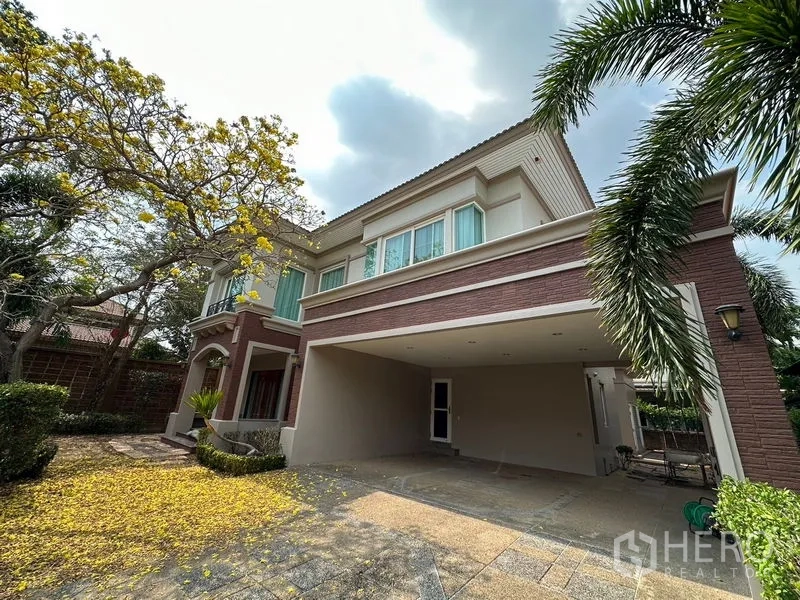 Detached House for rent or sale in Pak Kret, Nonthaburi - Covered two-car carport and wide windows beneath mature trees at a Nonthaburi home.