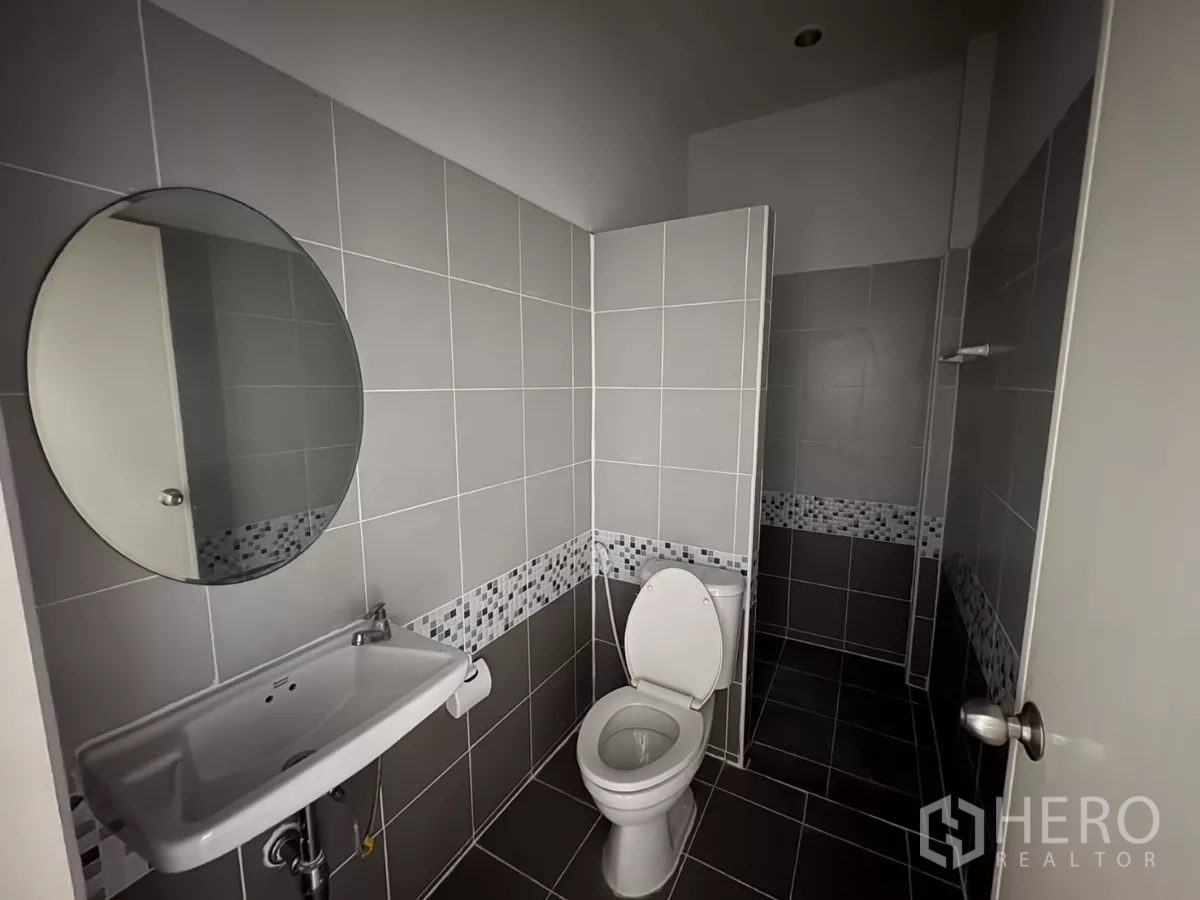 Factory for rent in Phra Samut Chedi, Samut Prakan - Second tiled bathroom with separate shower zone and round mirror.