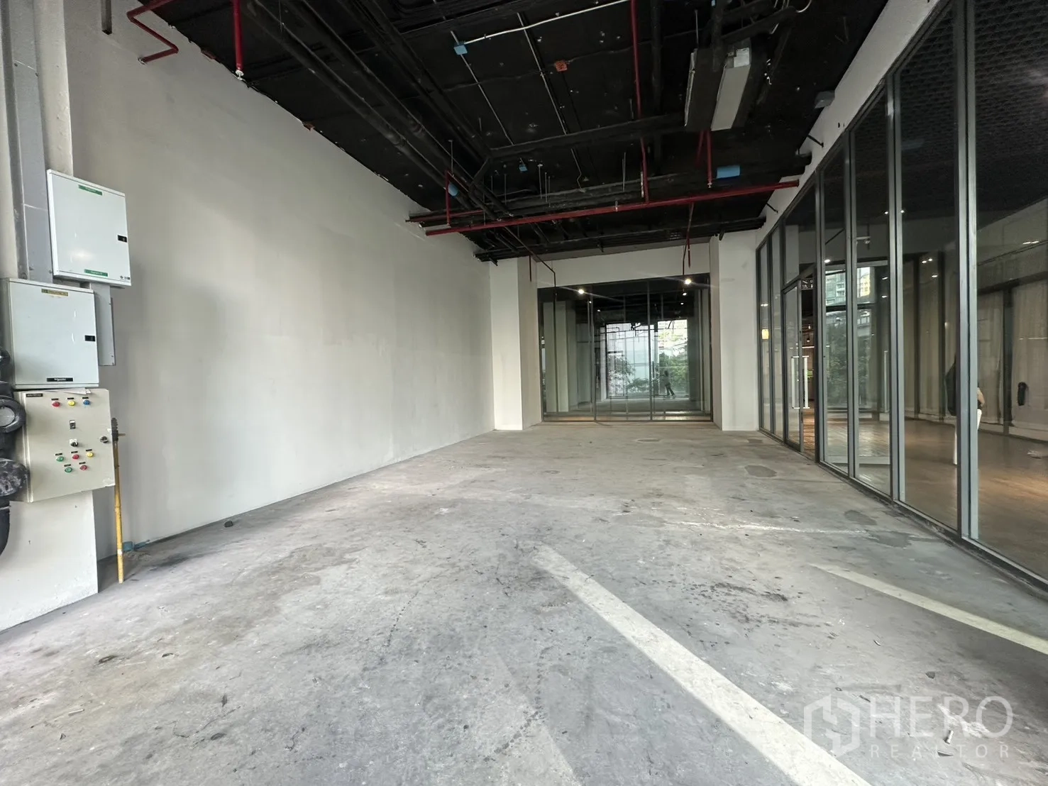 Retail Space for rent in Khlong Toei, Bangkok - Deep interior layout with white walls, exposed piping, and glass partitions.