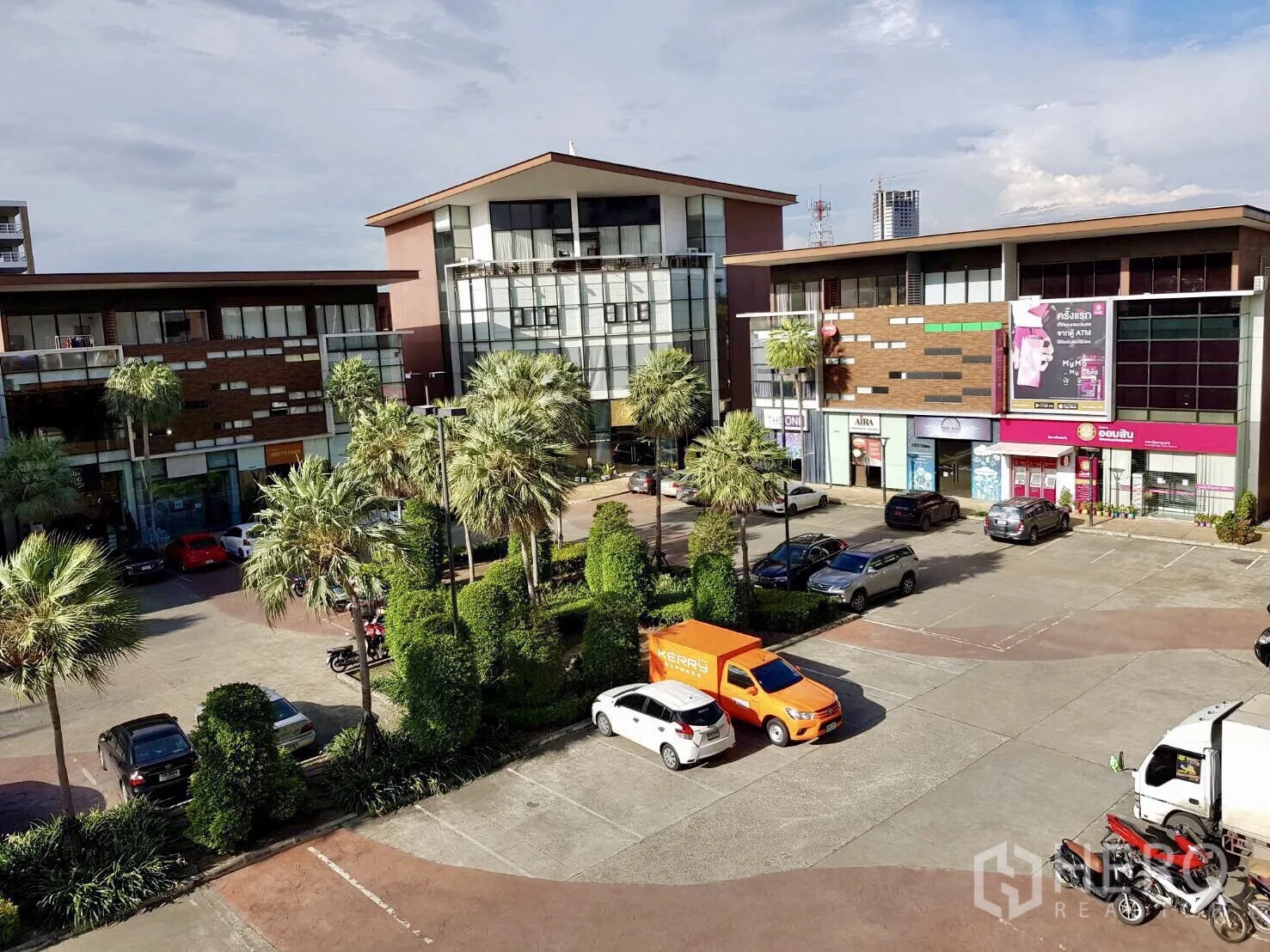 พื้นที่ขายปลีก ขายในPak Kret, Nonthaburi - มุมมองคอมมูนิตี้มอลล์ มีต้นปาล์ม อาคารพาณิชย์หลายยูนิต และที่จอดรถกว้าง