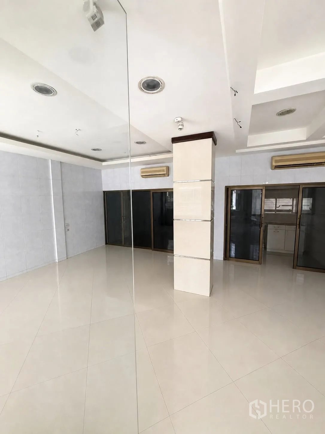 Shophouse for rent in Bang Rak, Bangkok - Bright open-plan ground floor with glossy white tiles, recessed ceiling lights, air conditioners and glass partitions.
