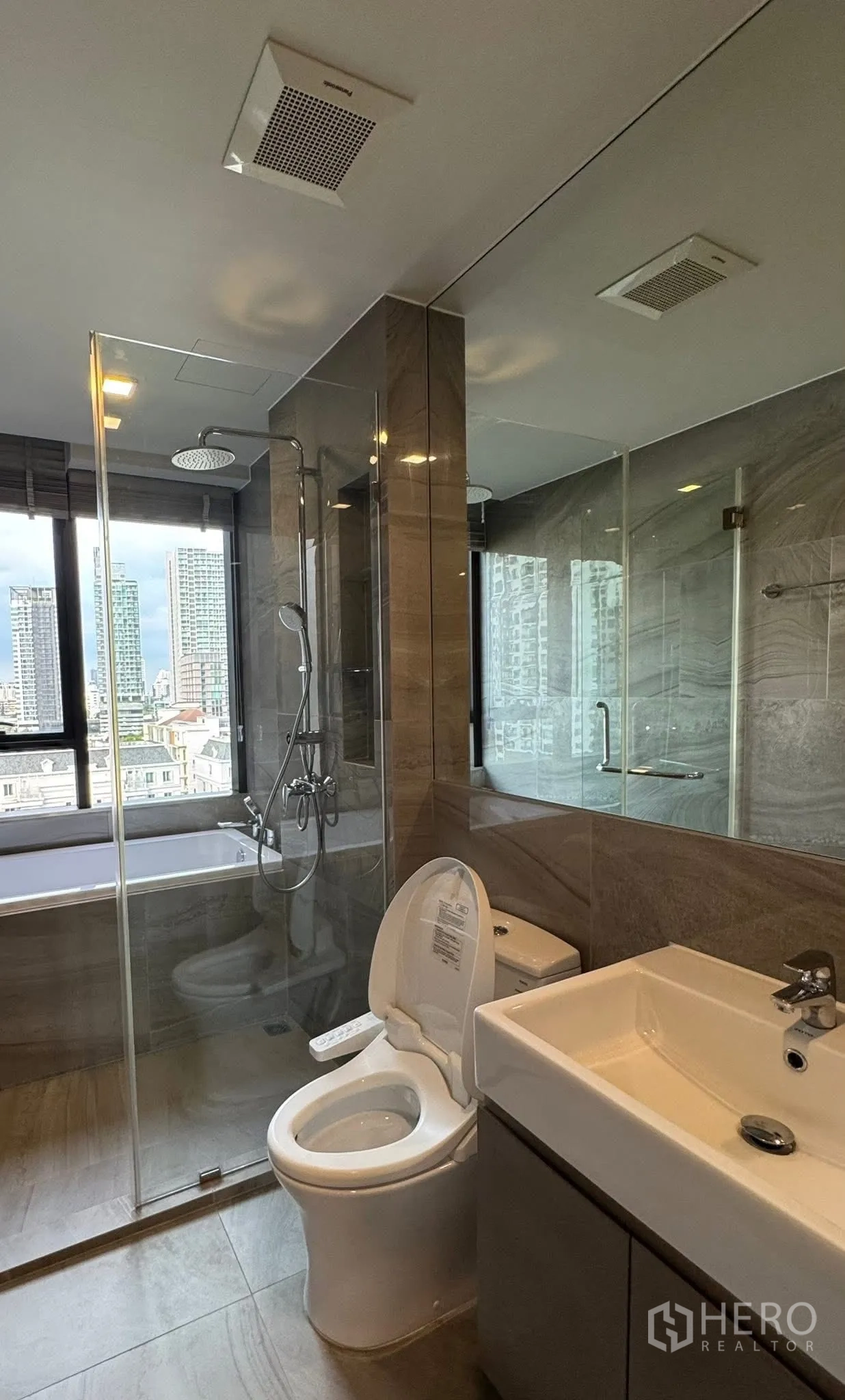 คอนโด for rent in Khlong Toei, Bangkok - ห้องน้ำพร้อมเรนชาวเวอร์และอ่างอาบน้ำข้างหน้าต่างมองเห็นวิวเมือง