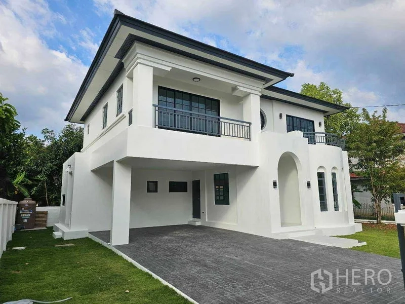 Detached House for sale in Thanyaburi, Pathum Thani - Two-storey white detached house with balconies, arched porch, and a covered carport.