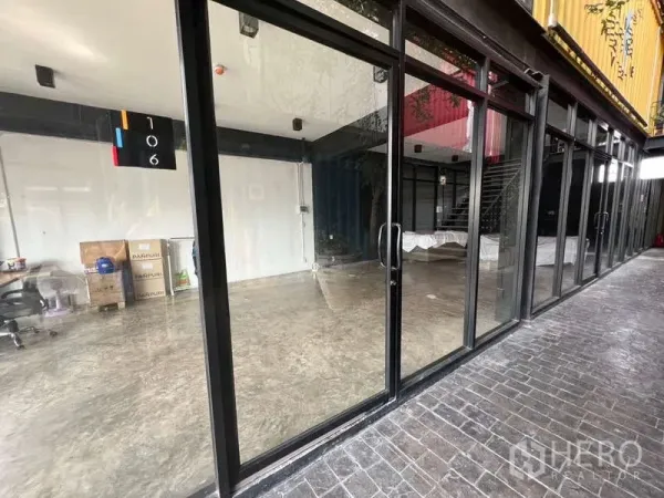 零售空间 出租 - 临街整面玻璃店面，黑色金属框与抛光水泥地，沿有顶走道。