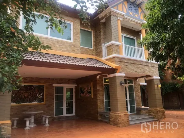 独立式住宅 出租或出售在Pak Kret, Nonthaburi - 正门与有顶车棚，带阳台与装饰立柱的立面