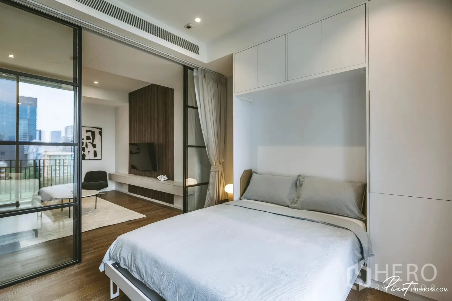 Condominium for rent in Pathum Wan, Bangkok - Bedroom with sliding glass partition to living room, double bed, and city outlook.