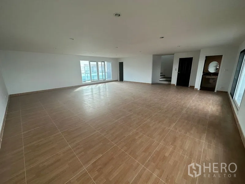 Home Office for rent in Bang Phli, Samut Prakan - Expansive wood-tile level with balcony doors and adjacent restroom.