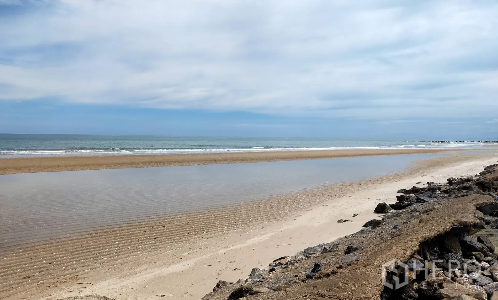 Land for rent or sale in Ban Laem, Phetchaburi - Long stretch of sandy beach with a breakwater and small surf.