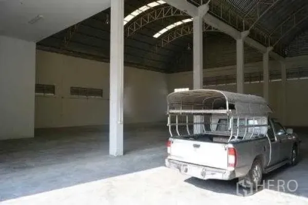 货栈 出租在Samut Sakhon - 仓库内部宽敞，拱形钢结构屋顶、混凝土地面，停着一辆皮卡。
