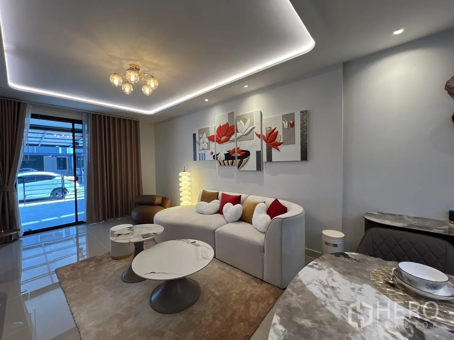 Townhouse for rent in Bang Phli, Samut Prakan - Bright lounge with a curved sofa, coffee tables, large window and LED strip ceiling lights.