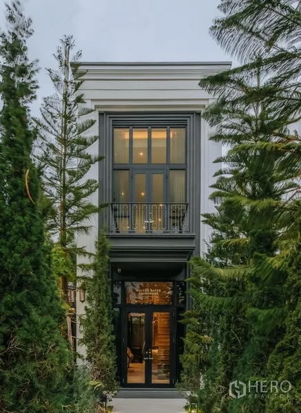 独立式住宅 出售在Saphan Sung, Bangkok - 优雅的狭长入口立面，被常青树环绕，上方带小阳台。