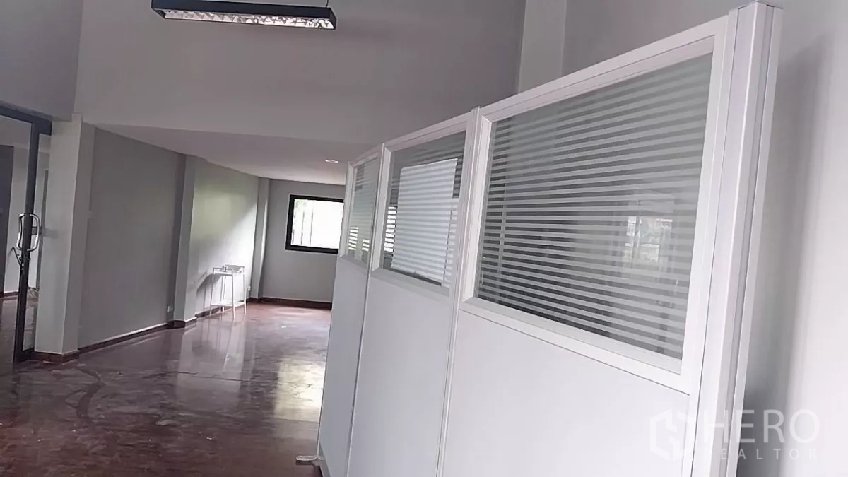 พื้นที่ขายปลีก ให้เช่า - โถงยาวพื้นเงา พร้อมฉากกั้นสีขาวบานเกล็ดและประตูกระจก