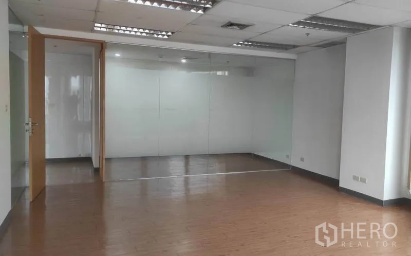 Office Space for rent in Bang Rak, Bangkok - Open-plan office in Silom with wood-look flooring, drop ceiling lights and a glass-partitioned meeting room.