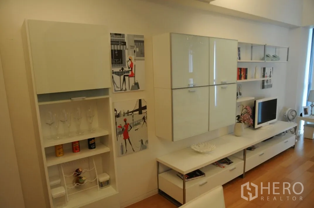 Condominium for rent or sale in Sathon, Bangkok - Bright living room with white built‑in wall cabinets, open shelving and TV unit.