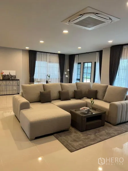 Detached House for rent in Bang Phli, Samut Prakan - Spacious living room with large sectional sofa, cassette ceiling air-conditioner and glossy floors.