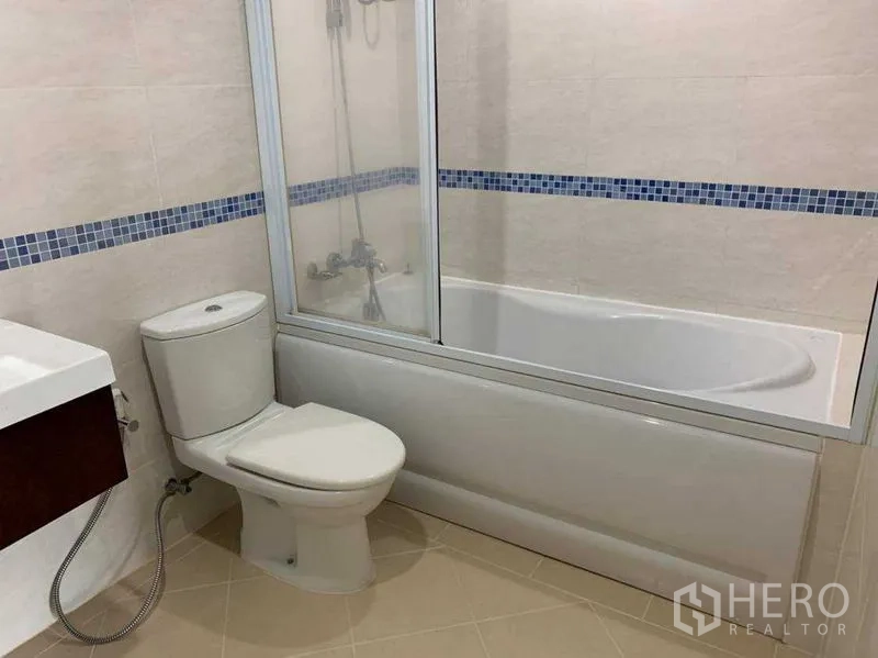 公寓 出租在Bang Rak, Bangkok - 浴室带浴缸与玻璃隔断、坐便器及蓝色马赛克装饰。