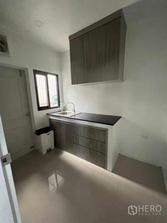 Detached House for rent in Samut Prakan - Another view of the kitchen showing sink, window and easy-clean tile flooring.
