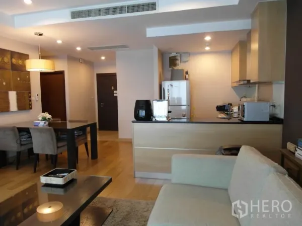 公寓 出租或出售在Sathon, Bangkok - 明亮客厅连接浅木色橱柜的开放式厨房、餐桌与入户走廊。