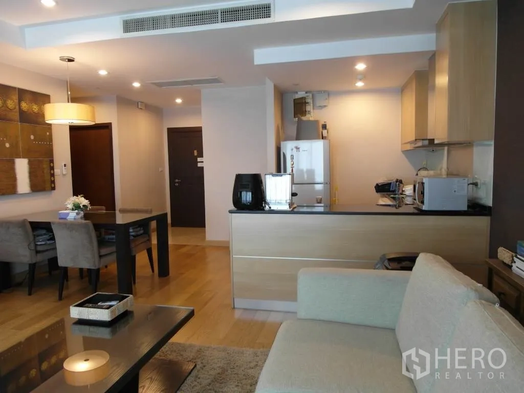 公寓 出租或出售在Sathon, Bangkok - 明亮客厅连接浅木色橱柜的开放式厨房、餐桌与入户走廊。