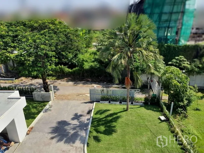 独立式住宅 出租在Phra Khanong, Bangkok - 俯瞰大门、草坪与棕榈树的院落景色。