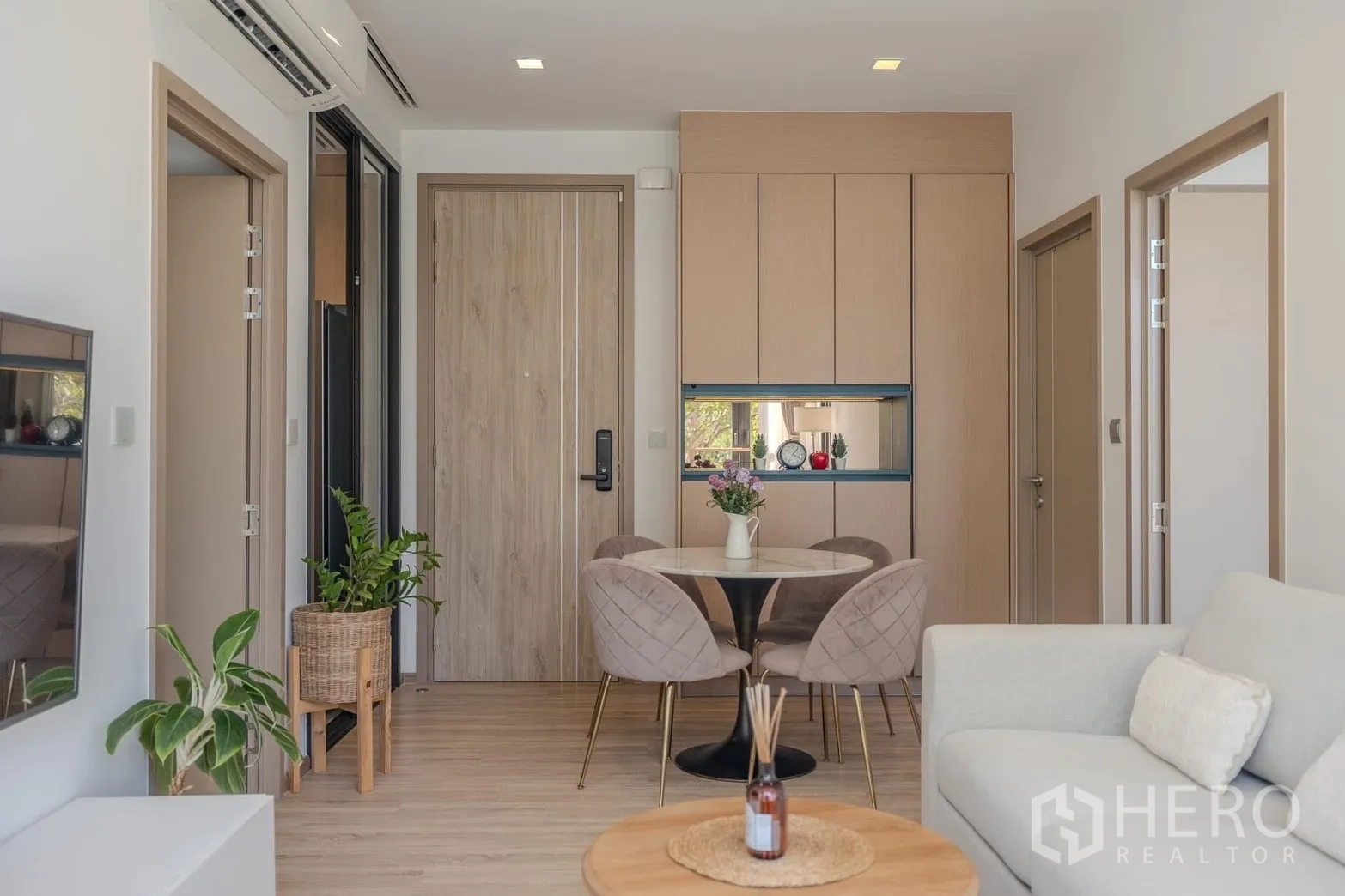 Condominium for rent in Watthana, Bangkok - Dining nook for four beside built-in storage and a wooden entrance door.