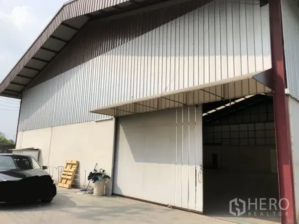 คลังสินค้า ให้เช่าในBueng Kum, Bangkok - ด้านหน้าโกดังกรุผนังเมทัลชีท เขตบึงกุ่ม พร้อมประตูบานเลื่อนขนาดใหญ่และลานจอดรถหน้าอาคาร.