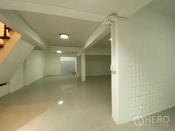 Detached House for rent in Bang Na, Bangkok - Wide view of the bright living area featuring columns, ceiling lights and a textured accent wall.