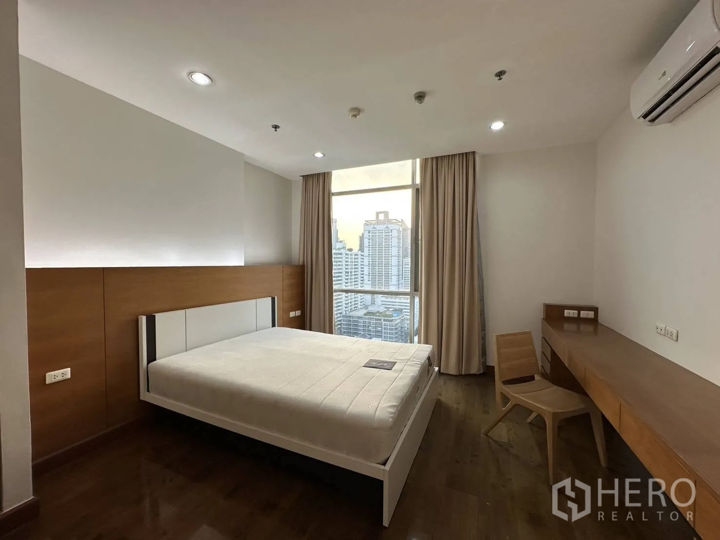 Condominium for rent in Watthana, Bangkok - Second bedroom with desk, air conditioner, and large window showing city views.