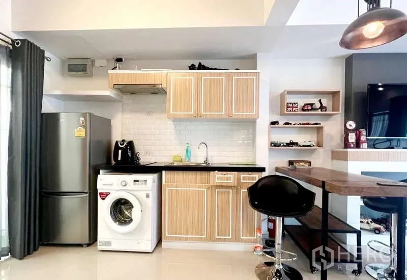 独立式住宅 出租在Bang Phli, Samut Prakan - 紧凑厨房，木纹橱柜、黑色台面、冰箱与洗衣机。