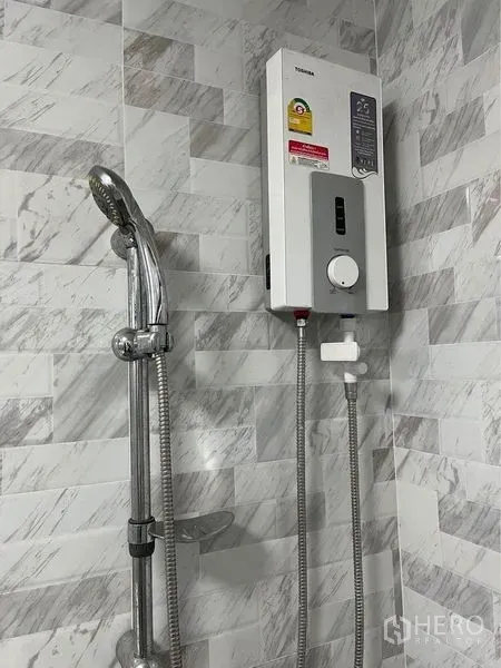 Home Office for rent in Bang Sue, Bangkok - Bathroom with handheld shower and electric water heater on marble-pattern wall tiles.