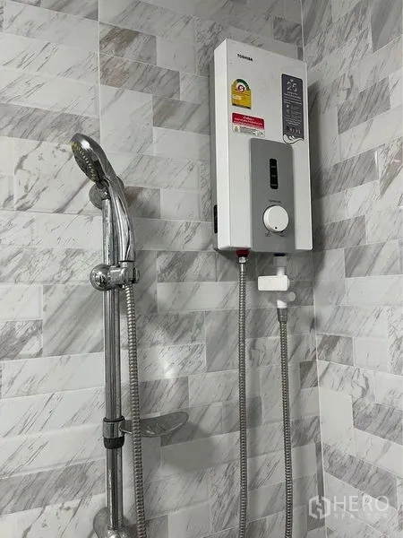 Home Office for rent in Bang Sue, Bangkok - Bathroom with handheld shower and electric water heater on marble-pattern wall tiles.