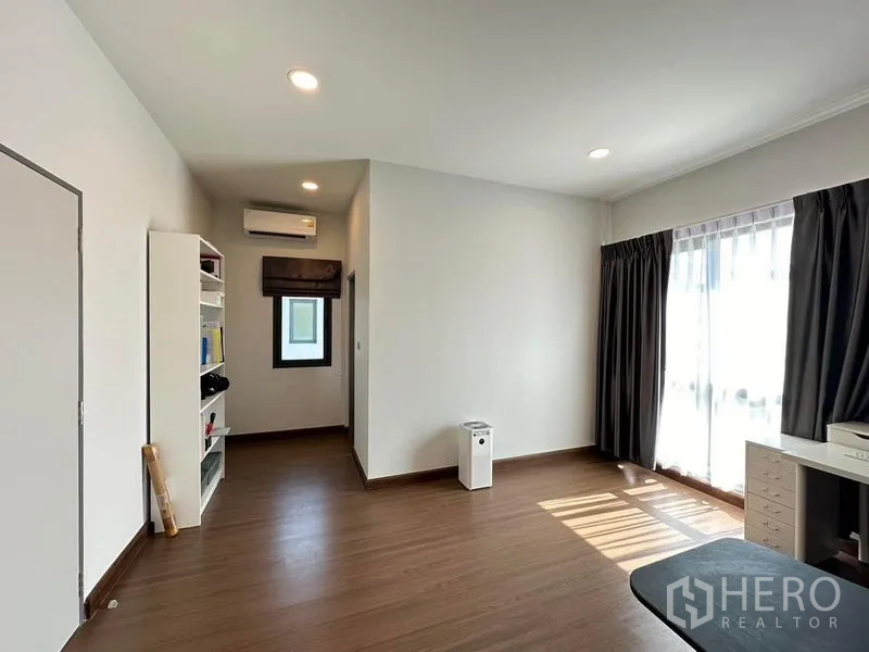 独立式住宅 出租在Bang Phli, Samut Prakan - 采光良好的多功能房，木地板、书架与带遮光窗帘的大窗。