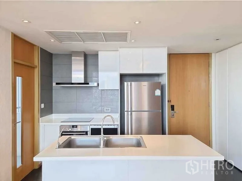 Condominium for rent in Watthana, Bangkok - Modern kitchen with island, double sink and stainless-steel appliances.