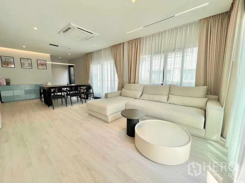 Detached House for rent in Bang Phli, Samut Prakan - Open-plan living and dining room with L-shaped sofa, full-height windows and light wood floors.