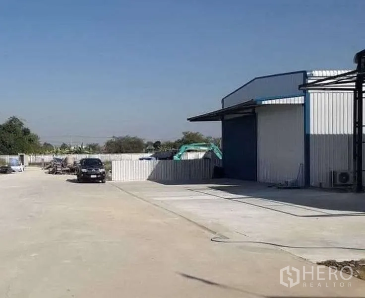 货栈 出租在Khlong Sam Wa, Bangkok - 宽阔混凝土场地与蓝色仓库仓门，周边围栏，卡车进出便捷，曼谷Khlong Sam Wa。