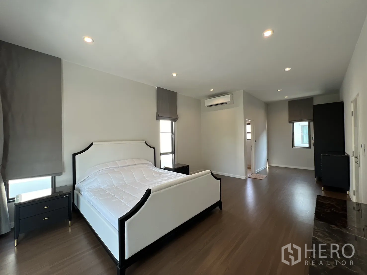 บ้านเดี่ยว for rent in Bang Phli, Samut Prakan - ห้องนอนใหญ่กว้าง เตียงสีขาว พื้นไม้ แอร์ และโต๊ะข้างเตียง
