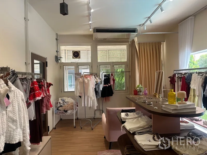 Retail Space for rent in Khlong Toei, Bangkok - Shop interior showing windows with greenery outside, air conditioner, garment racks, and a display counter.