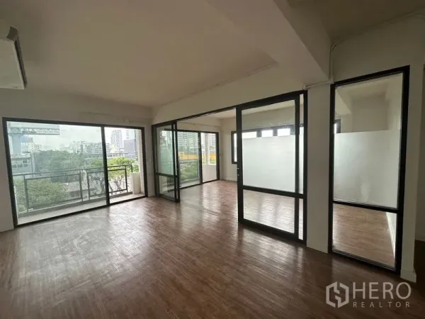 办公空间 出租在Sathon, Bangkok - 采光充足的开放式办公室，木纹地板、玻璃隔间与带城市景观的阳台。
