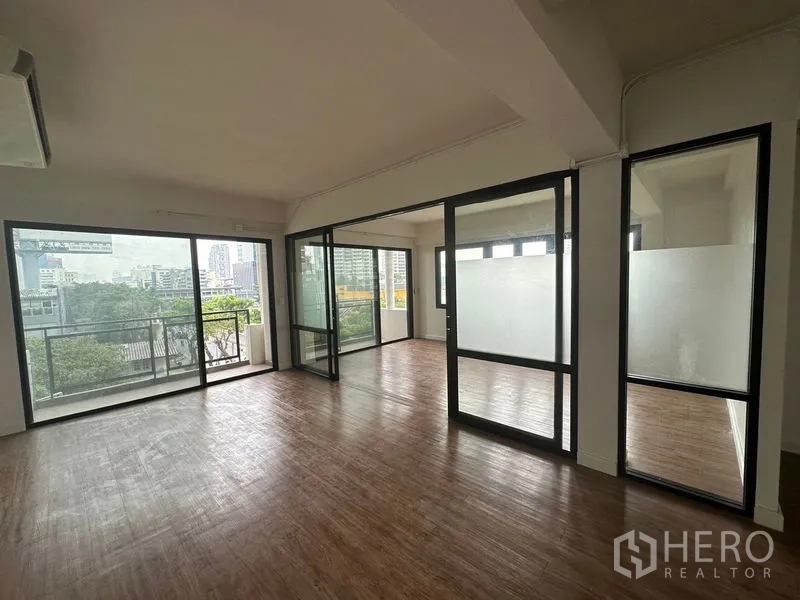 办公空间 出租在Sathon, Bangkok - 采光充足的开放式办公室，木纹地板、玻璃隔间与带城市景观的阳台。
