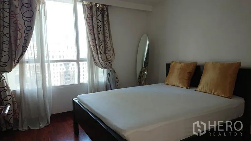 Condominium for rent in Pathum Wan, Bangkok - Guest bedroom with gold pillows, standing mirror and sheer curtains by a bright window.