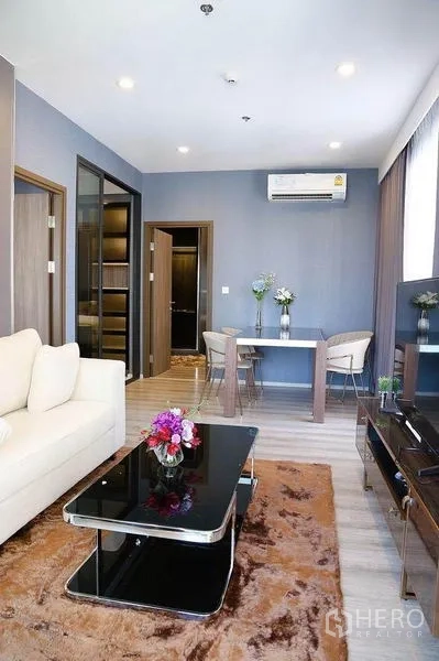 คอนโด ให้เช่าในHuai Khwang, Bangkok - โถงนั่งเล่น–รับประทานอาหารแบบเปิดโล่ง โซฟา โต๊ะกลางกระจกดำ ทีวี และพรม