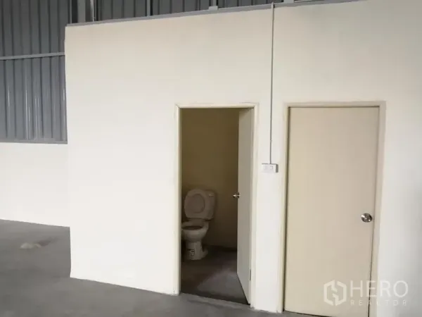 Warehouse for rent in Phra Samut Chedi, Samut Prakan - Clean restroom inside the warehouse with flush toilet and adjacent utility room.