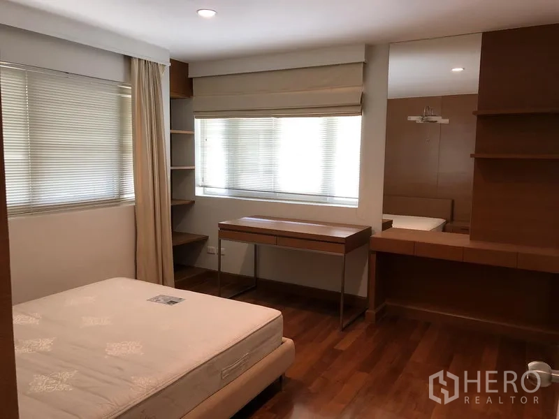 Detached House for rent in Watthana, Bangkok - Bedroom with wood floors, large windows, built-in desk and shelving.
