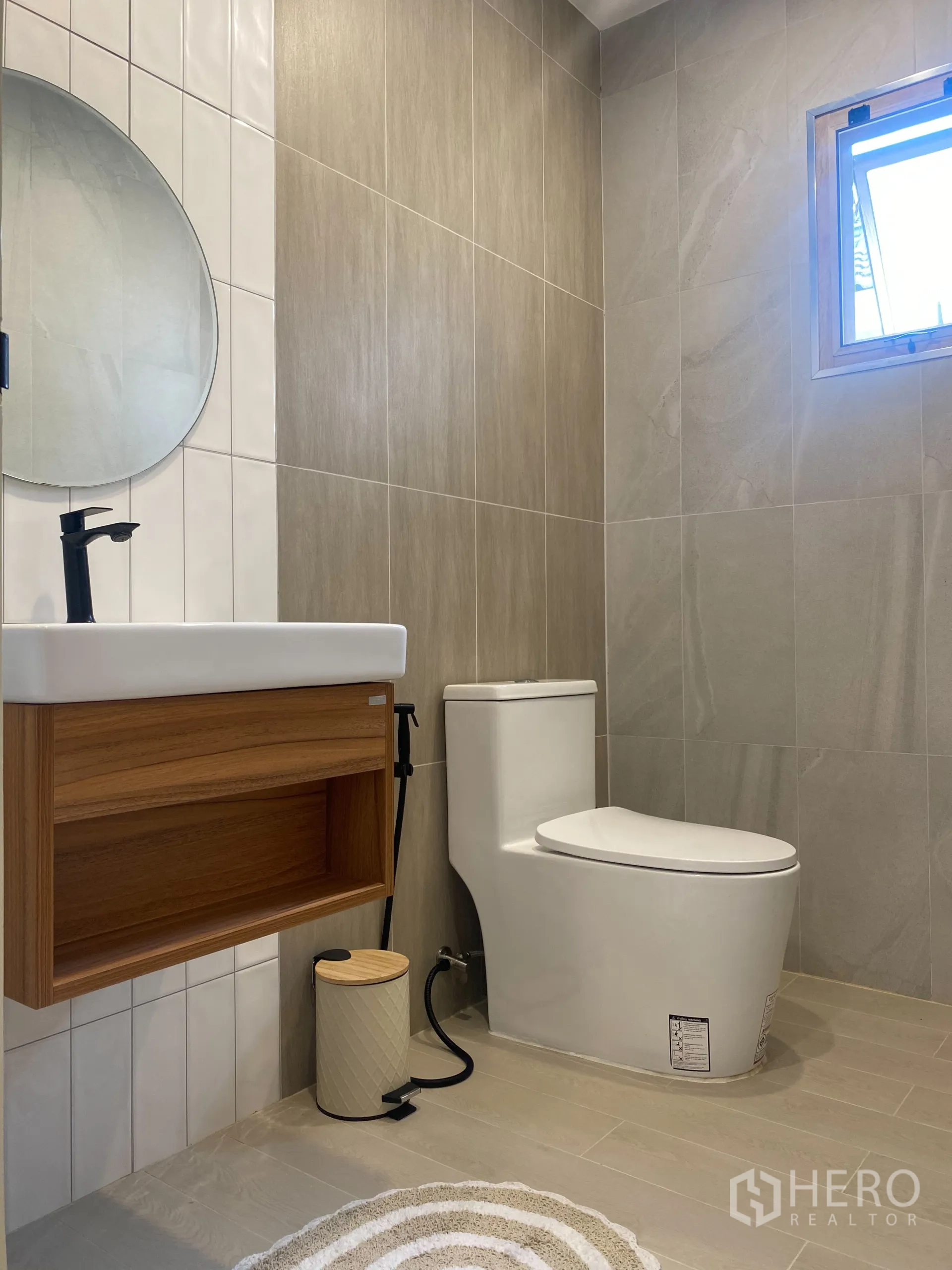 独立式住宅 出售在Suan Luang, Bangkok - 客用卫浴，圆镜、木质浴柜与中性色墙砖。